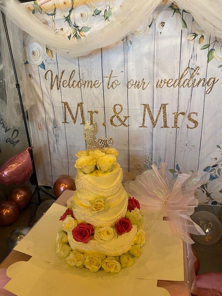 A three-tier yellow celebration cake decorated with red and yellow roses